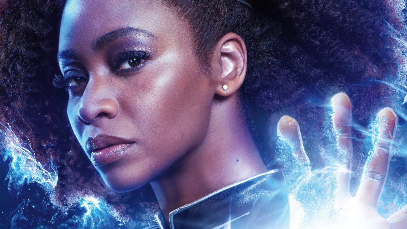 Una mujer con cabello negro y una camisa azul sosteniendo una bola brillante (monica rambeau, los maravillas, película, marvel, teyonah parris)