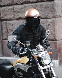 Stylischer Motorradfahrer in schwarzer Lederjacke mit Cruiser mit goldenen Akzenten