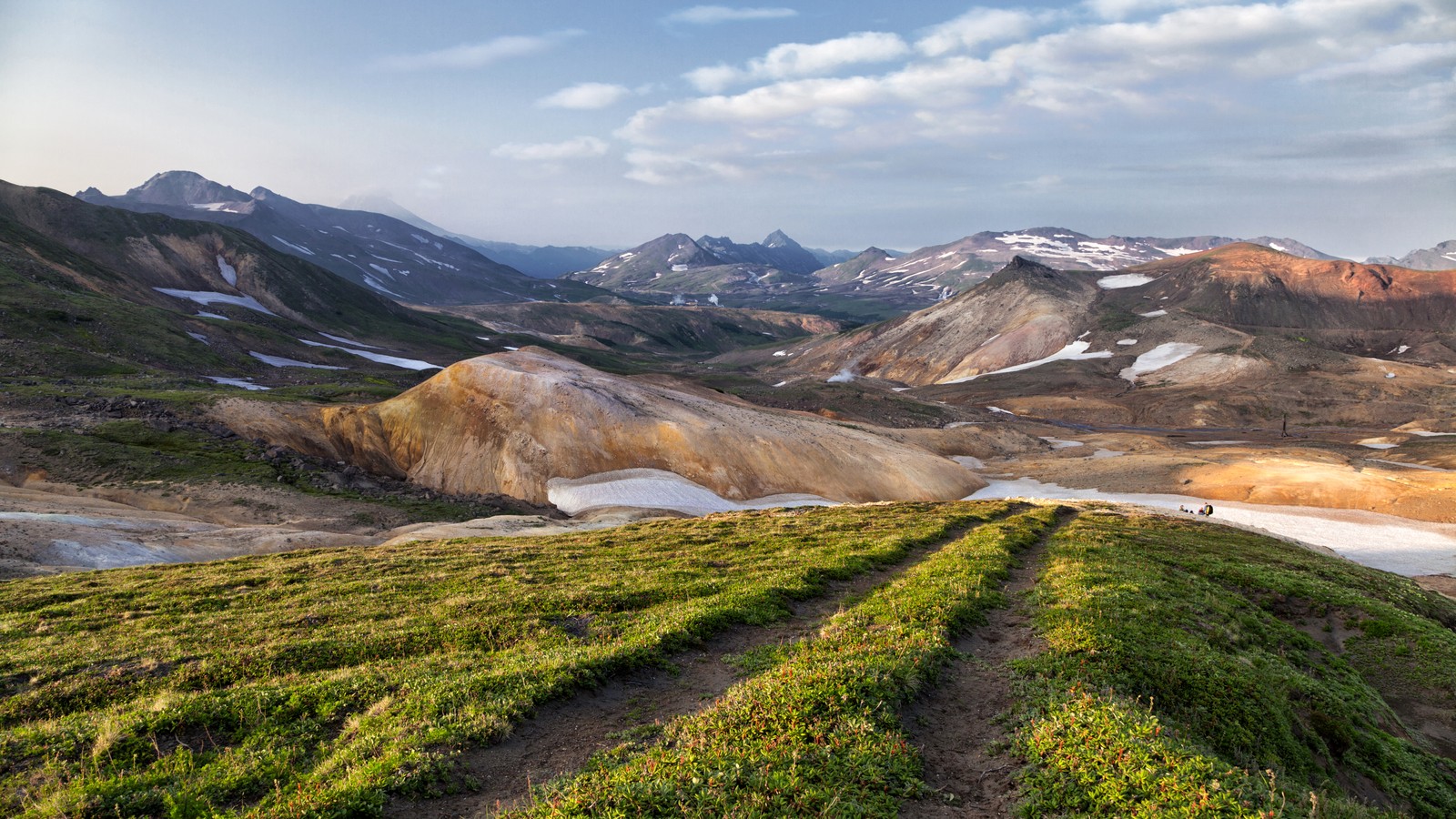 Uma vista de um campo gramado com neve e montanhas ao fundo (vulcões da kamchatka, montanha, natureza, formas montanhosas, terras altas)