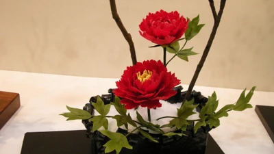 Elegante Ikebana-Anordnung mit roten Blumen und Zweigen