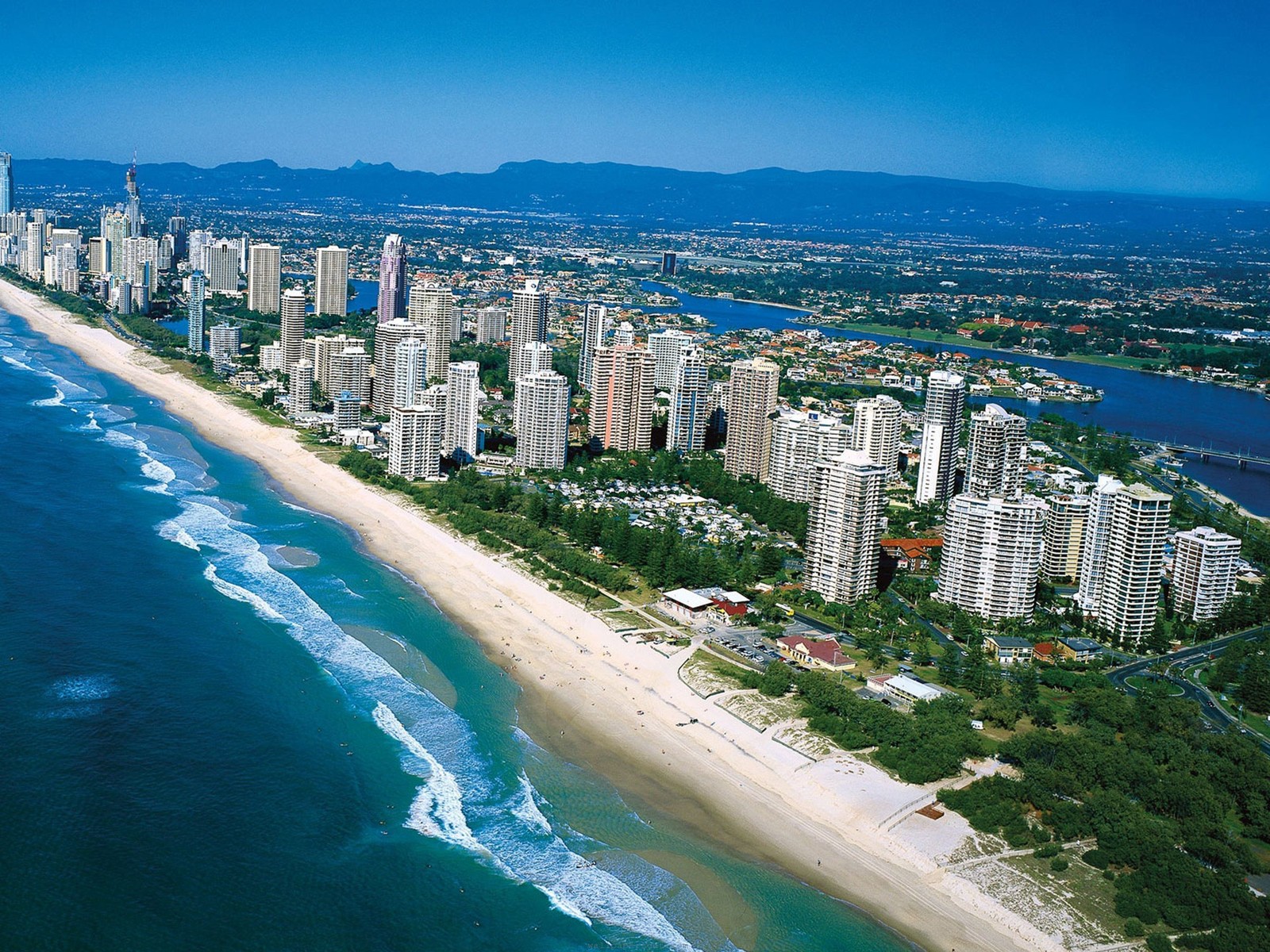 Uma vista de uma praia e uma cidade com uma longa praia de areia branca (área urbana, costa, cidade, dia, vista aérea)