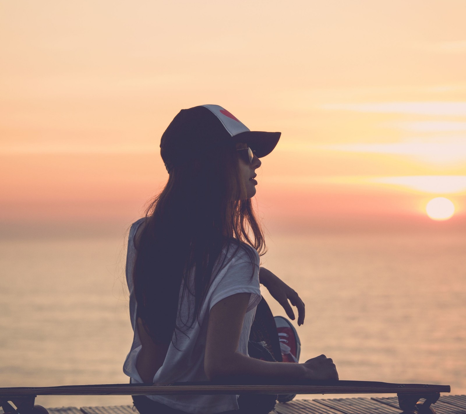 Une femme arabe assise sur un banc regardant l'océan (4k, beau, brunette, casquette, mignon)