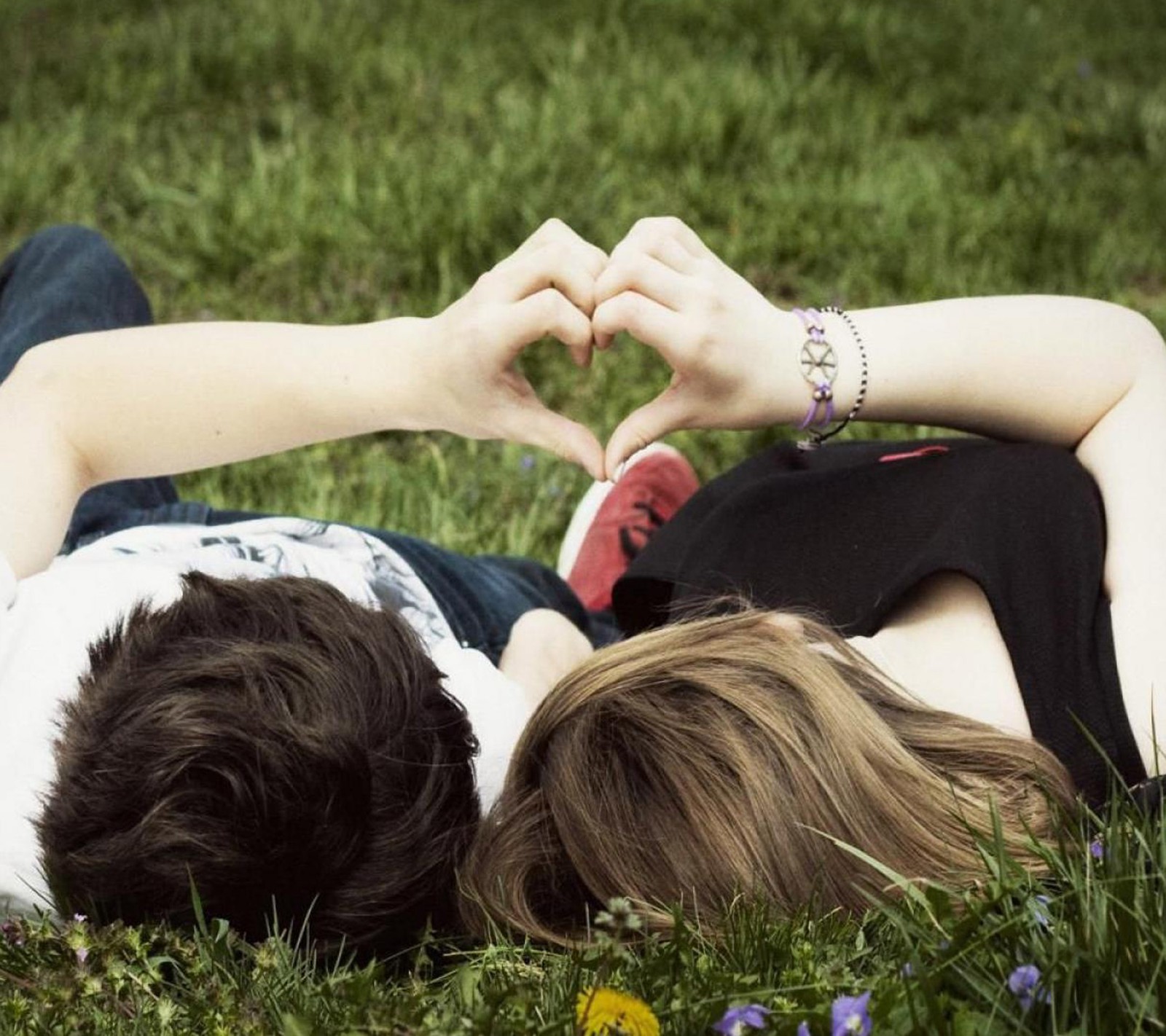 Deux personnes sont allongées sur l'herbe formant un cœur (amour, natureal, romance)