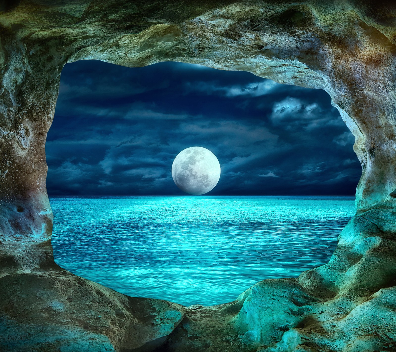 A view of a full moon rising over the ocean from a cave (blue, moon, ocean)