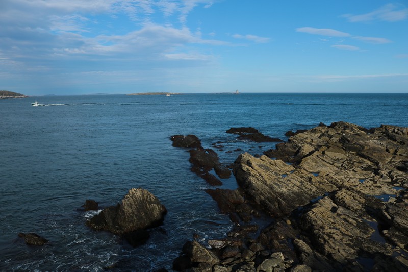 Лодка находится на воде рядом с камнями (море, берег, бухта, водоем, океан)