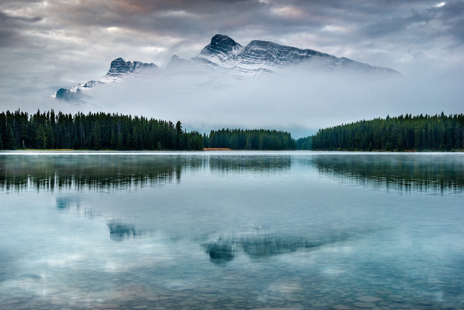 Berge spiegeln sich im wasser eines sees mit einem berg im hintergrund (banff, natürliche landschaft, natur, gewässer, reflexion)