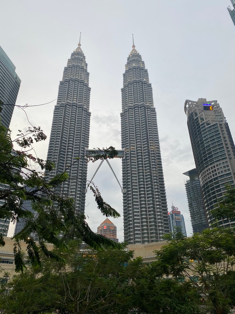 В городе много высоких зданий с часами на вершине (петронас, кuala lumpur, небоскреб, башенный блок, архитектура)