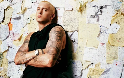 Eminem mit Tattoos, selbstbewusst gegen eine Wand posierend, die mit handgeschriebenen Notizen bedeckt ist, die Reflexion und Genesung in der Hip-Hop-Musik symbolisieren.