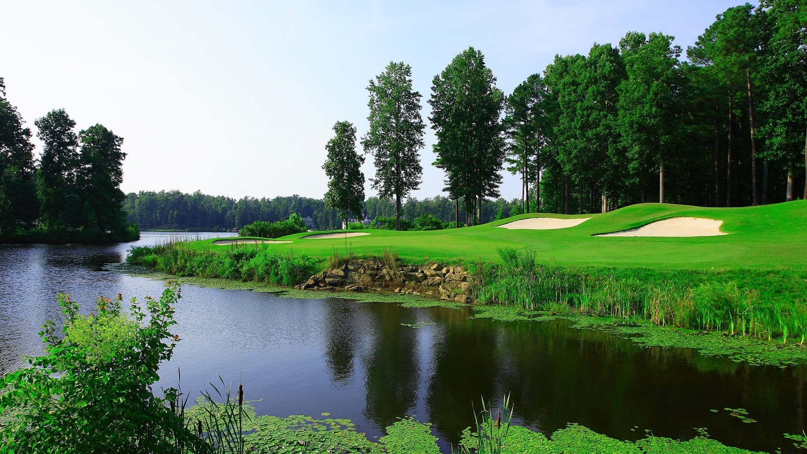 A view of a golf course with a pond and a green (nature, slide show, water, reflection, water resources)