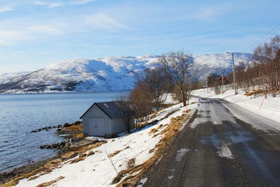 Route d'hiver le long d'un fjord recouvert de neige dans le paysage alpin de Norvège