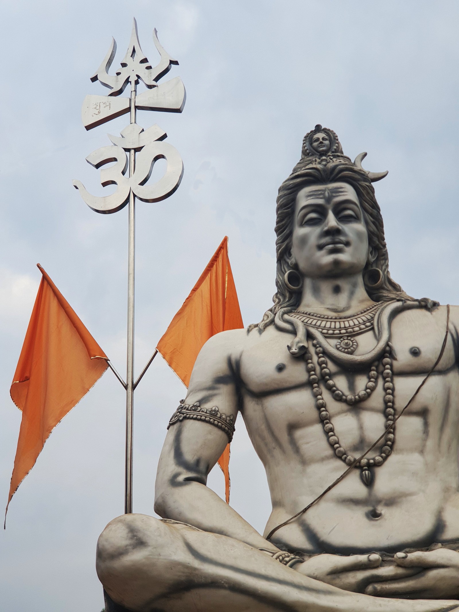 Há uma estátua de um homem sentado em um pedestal (bhole, har har mahadev, jai bholenath, senhor, senhor shiva)