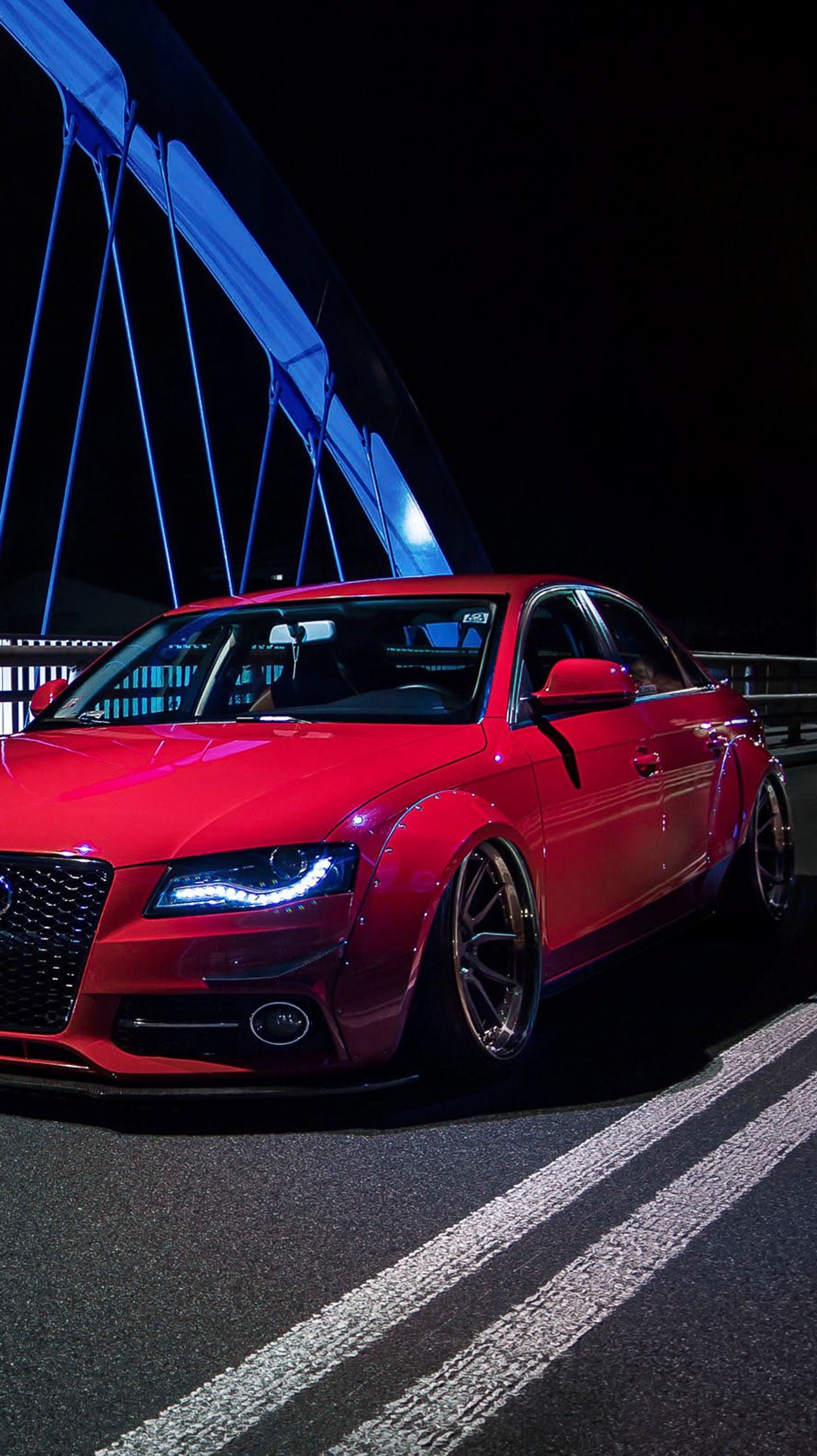 Une voiture rouge garée sur un pont la nuit avec un pont en arrière-plan (audi, voiture, œil, nuit, rouge)