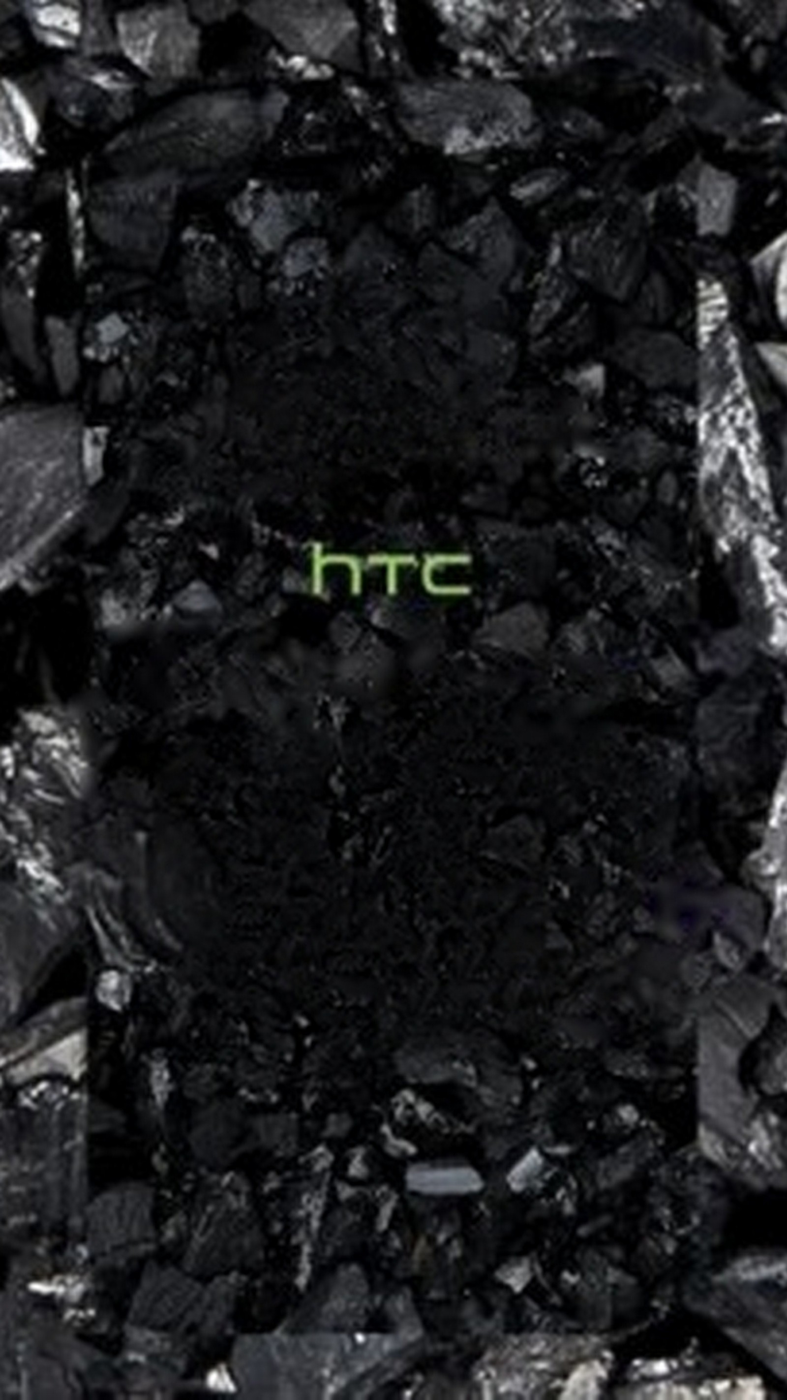 A close up of a cell phone on a pile of coal (htc, technology, wallpaper)