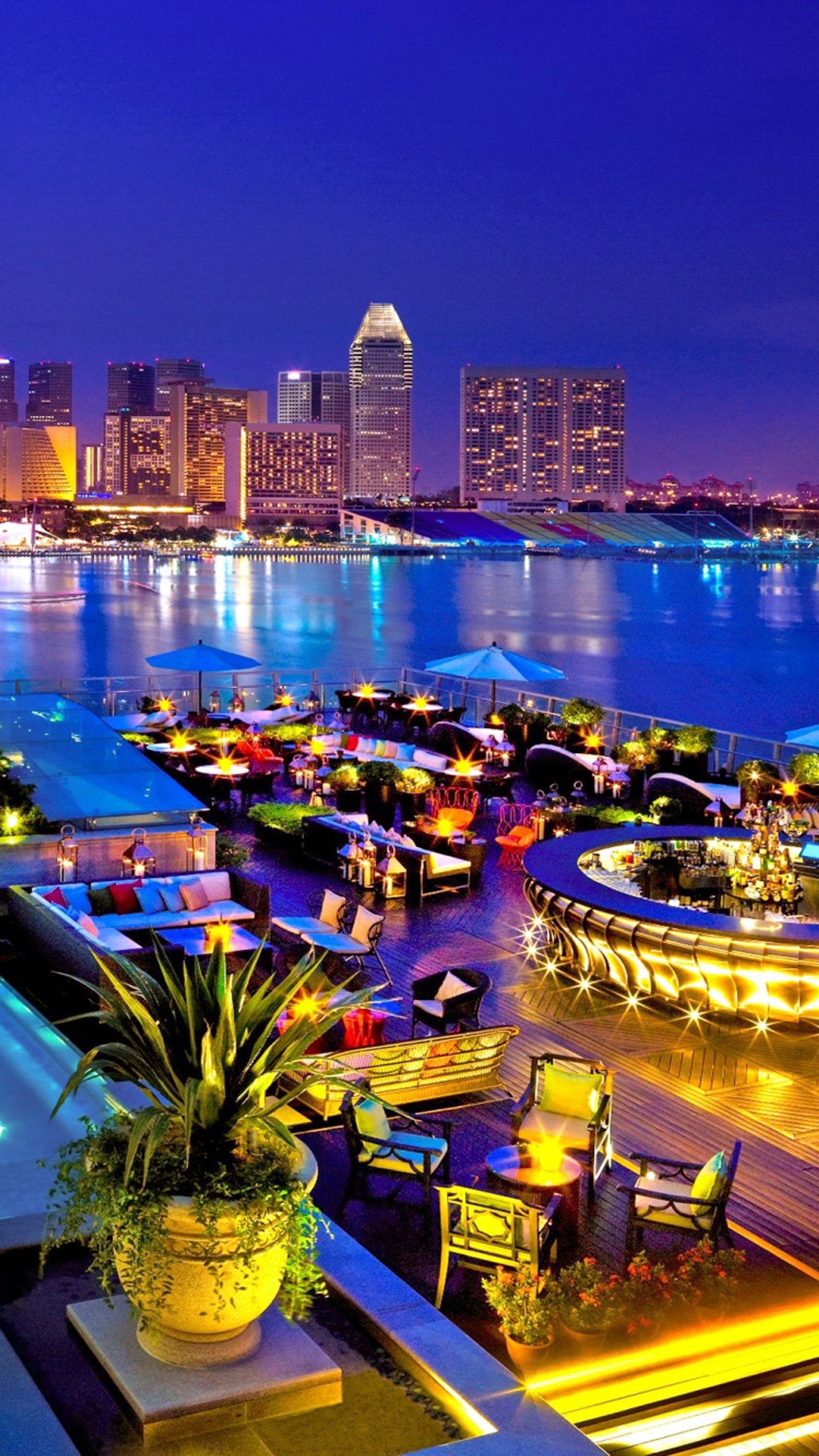 Vista noturna de uma cidade com uma piscina e barcos na água (cores, paisagem, natureza, foto)