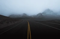 Autoroute enveloppée de brouillard à travers un terrain montagneux majestueux