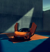 McLaren GT en orange frappant avec les portes levées, présenté dans un cadre urbain minimaliste.