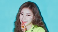 Chaeryeong de ITZY sonriendo con un helado colorido contra un fondo azul vibrante.