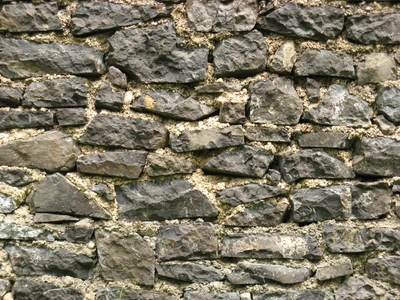 Mur en roche volcanique texturé avec des galets et des débris