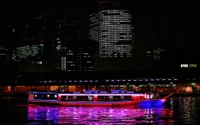 Cenário urbano noturno vibrante de Tóquio com reflexo de barco iluminado