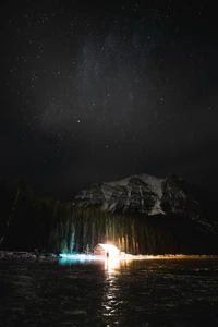 Reflexión Nocturna Serena: Una Cabaña junto al Río Bajo un Cielo Estrellado