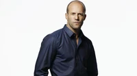 Jason Statham em uma camisa escura e elegante, exalando confiança e sofisticação.