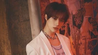 Choi Beomgyu from TXT posing with an intense gaze against a backdrop of vibrant, weathered posters.