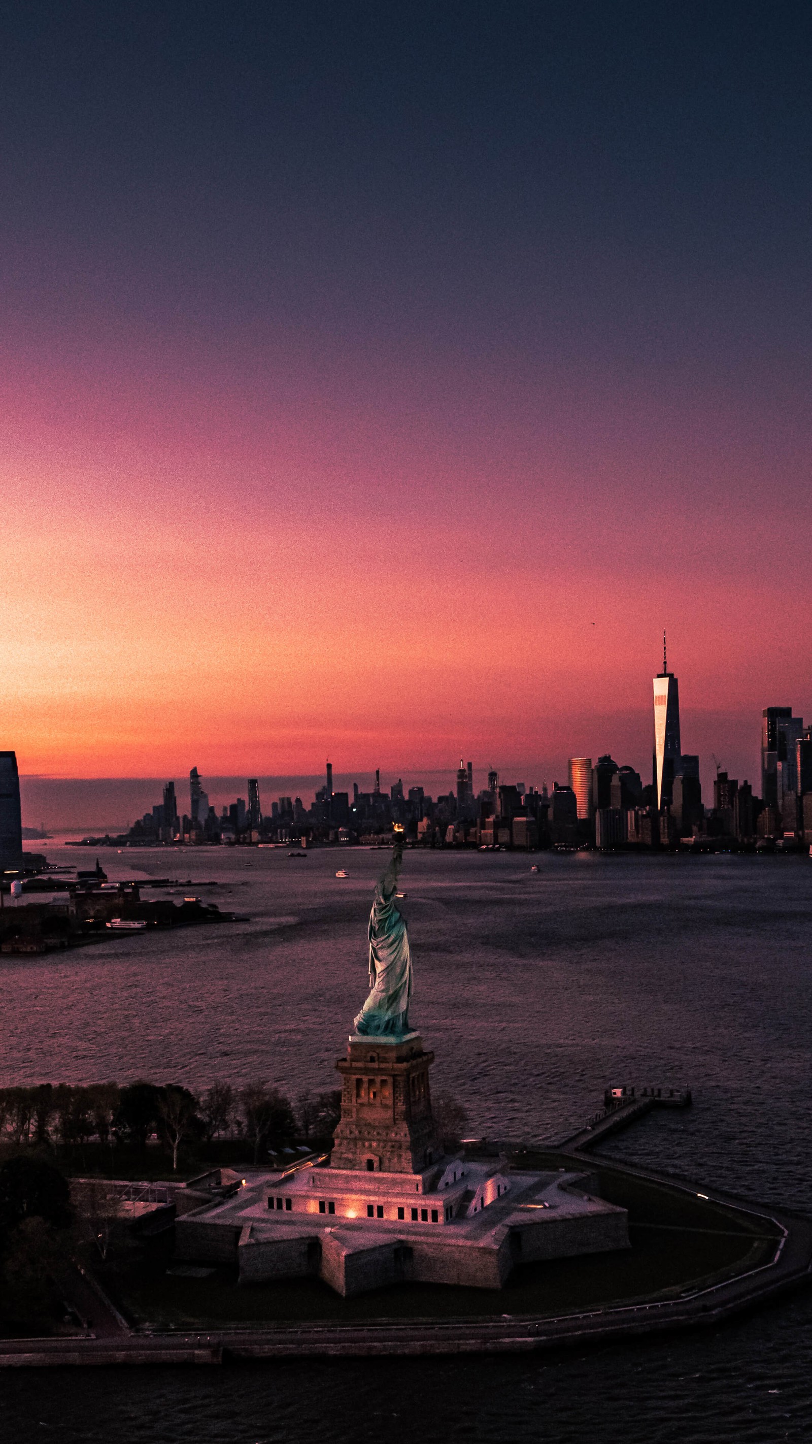 Vue arabe de la statue de la liberté au coucher du soleil avec la silhouette de la ville en arrière-plan (new york, statue de la liberté, atmosphère, bâtiment, crépuscule)