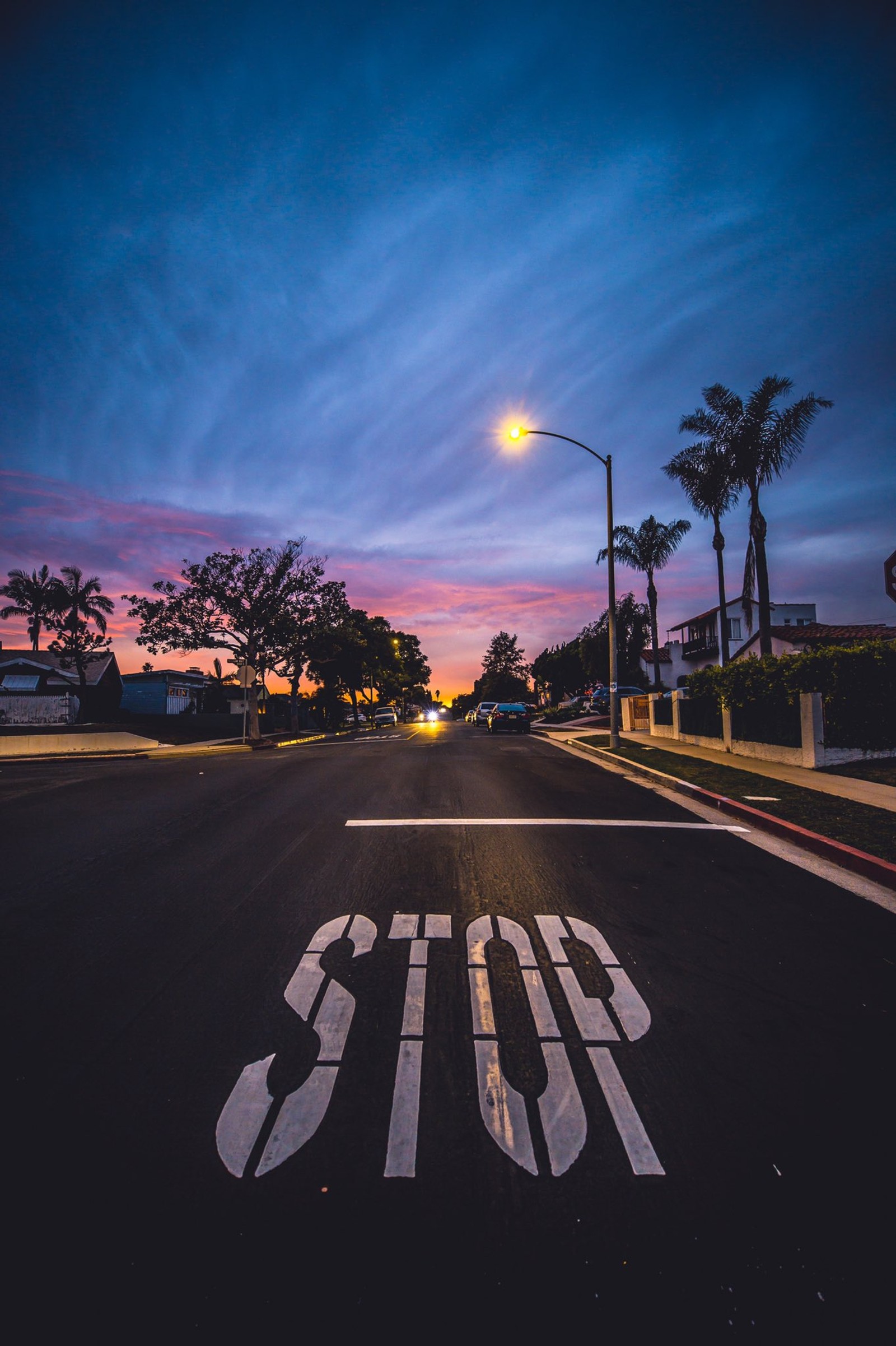 Ein stoppschild, das auf der straße vor einer straßenlaterne gemalt ist (abend, kalifornien, california, reise, lichter)