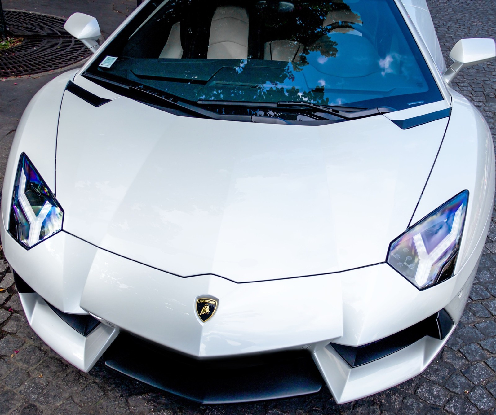 Une voiture de sport blanche garée sur une rue en pavés (incroyable, avnetador, voiture, blanc)