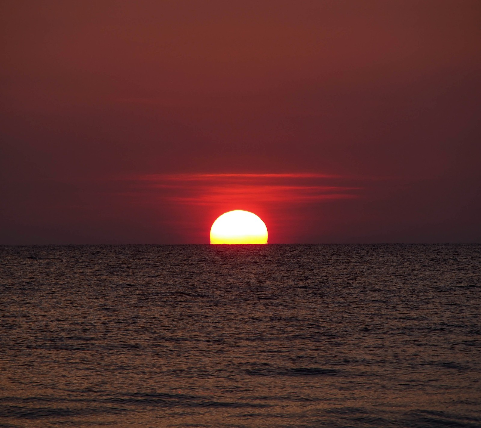 Arafed view of a sunset over the ocean with a boat in the distance (landscape, nature, sun, sunset, water)