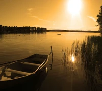 Goldener Sonnenuntergang über ruhigem Wasser mit einem Boot