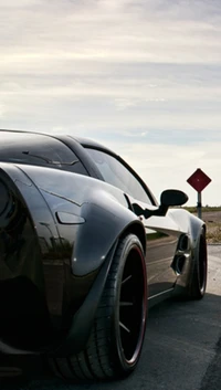 Sleek Black Sports Car Against a Scenic Sky