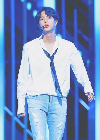 Jin of BTS performing on stage in a stylish outfit with a charismatic presence.