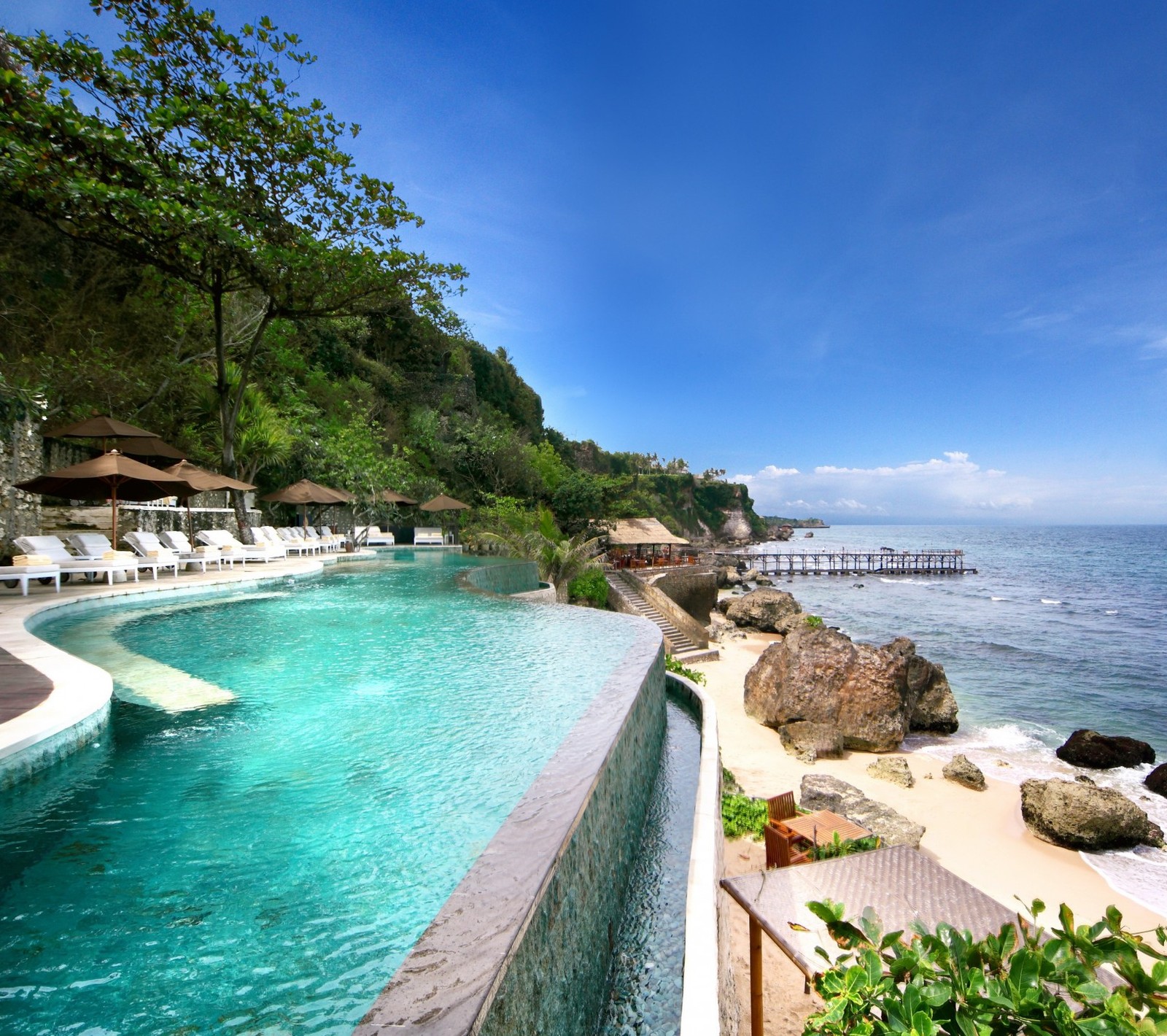 Uma vista de uma piscina com espreguiçadeiras e uma praia ao fundo (melhores hotéis, mar, spa, turismo, vista)