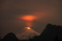 Sommet lumineux d'un volcan bouclier sous un ciel nocturne dramatique