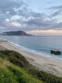 Praia Cleópatra ao crepúsculo: ondas serenas e horizonte montanhoso na Turquia