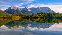 Majestätische Bergreflexionen in einem ruhigen See, umgeben von herbstlichen Wäldern