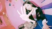 Dahyun de TWICE extendiendo juguetonamente la mano, rodeada de un vibrante fondo rosa.