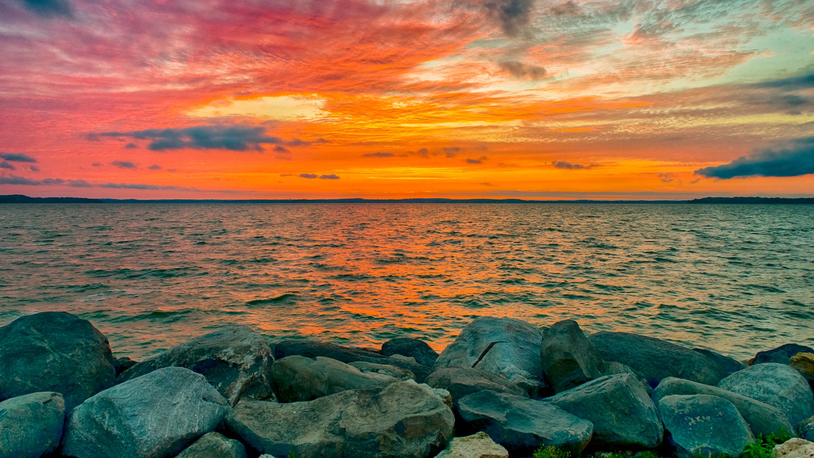 Une vue d'un coucher de soleil sur l'océan avec des rochers au premier plan (coucher de soleil, horizon, mer, eau, océan)