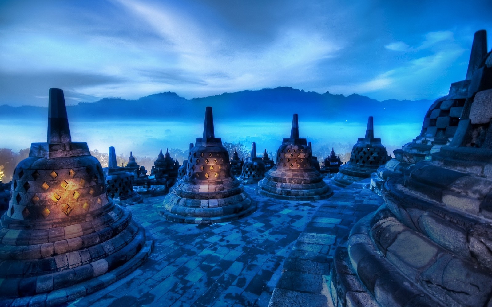 Aussicht auf eine gruppe von steinstupas mit einem berg im hintergrund (wahrzeichen, indonesien, archäologische stätte, stadtbild, historische stätte)