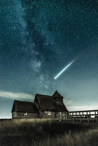 Una casa serena bajo un cielo nocturno estrellado con una estrella fugaz y la Vía Láctea iluminando la atmósfera.