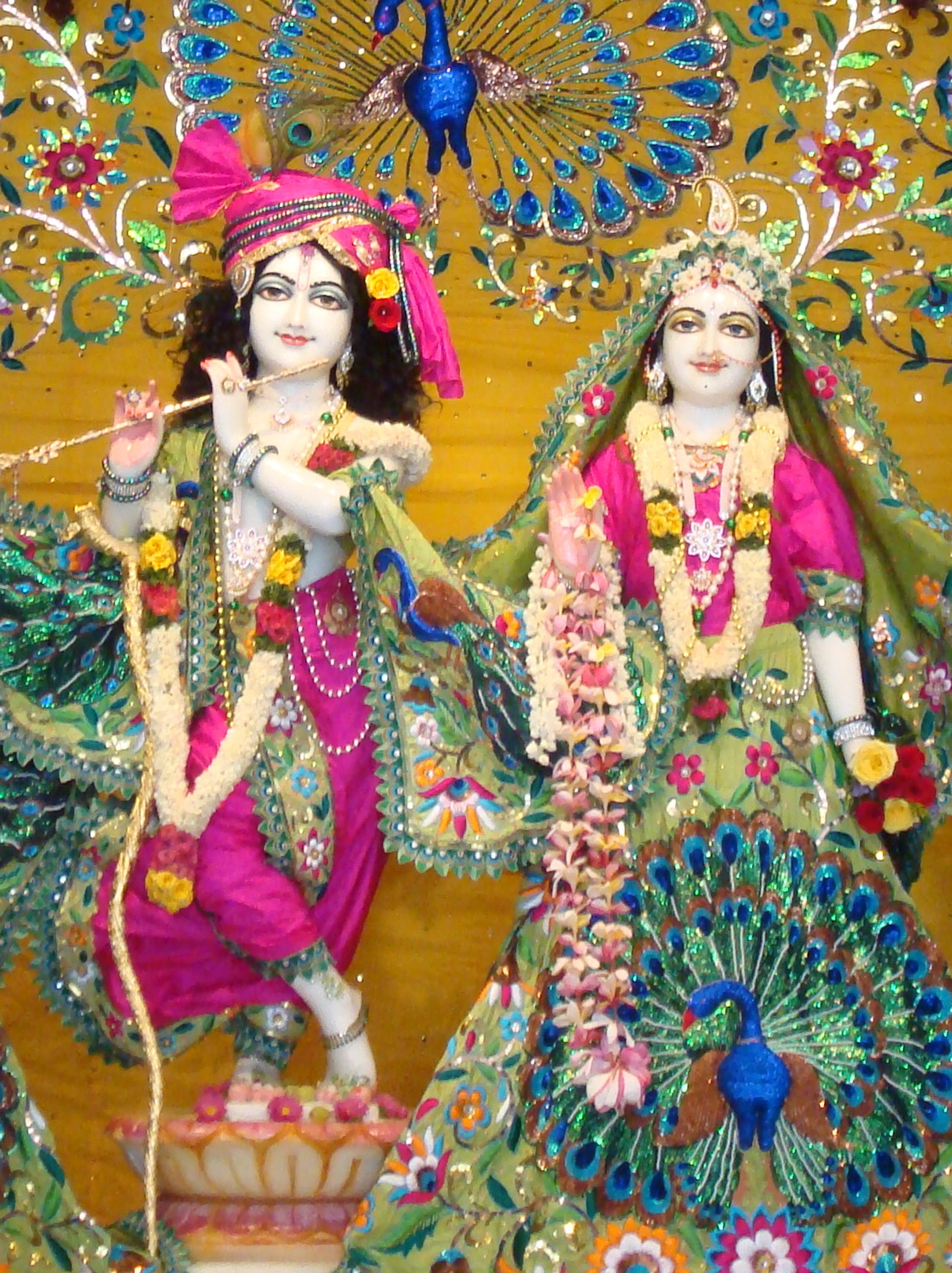 A close up of two statues of hindu deities with peacocks (krishna, radhae)