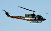 Military helicopter in flight with a distinctive tiger-striped tail and vibrant color scheme.