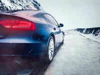 Audi branco com rodas de liga leve em uma estrada nevada