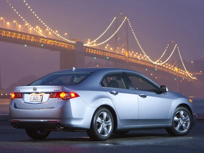 O sedã Acura TSX estacionado perto de uma ponte cênica ao anoitecer, exibindo seu design elegante e estilo automotivo moderno.