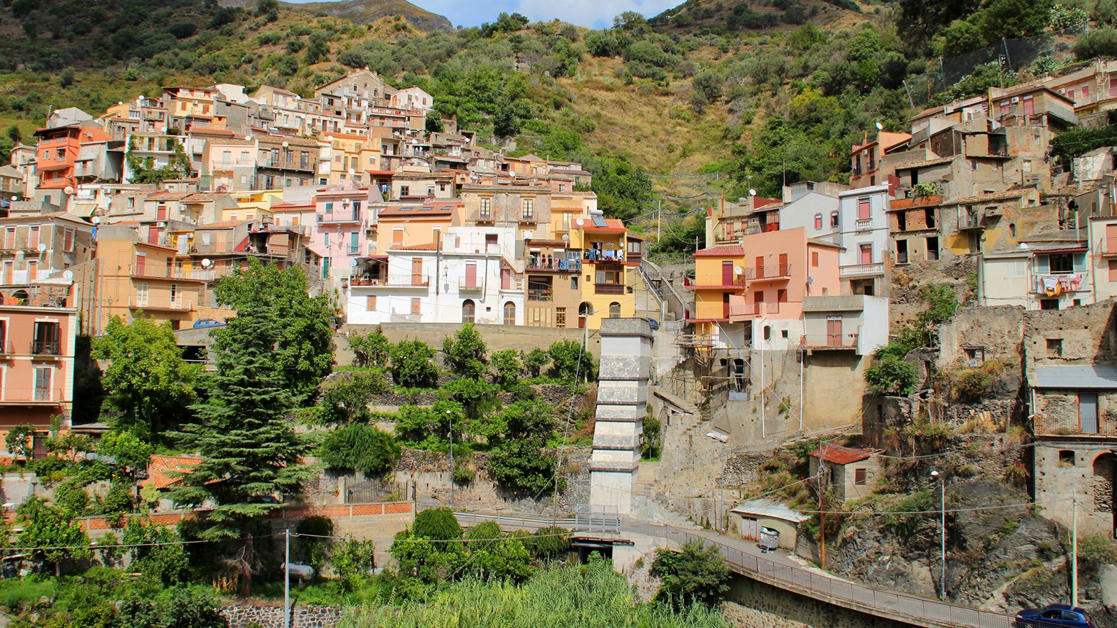 Vista aérea de un pueblo en una ladera con un puente (ciudad, montaña, pueblo de montaña, pueblo, vecindario)