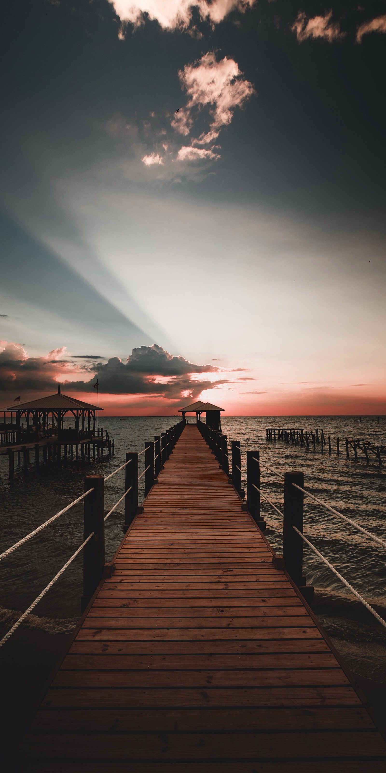 Arafed pier with a wooden walkway leading to a pier (water, atmosphere, nature, afterglow, wood)