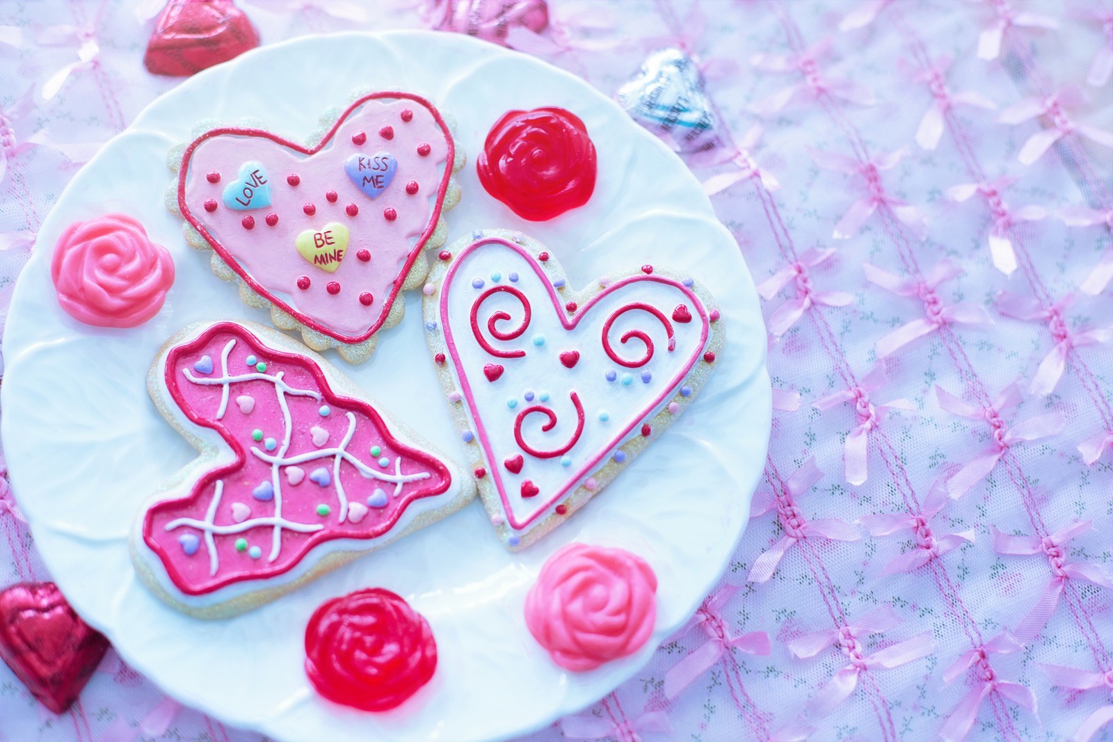 Hay tres galletas en un plato con glaseado rosa y caramelos (día de san valentín, festivo, corazón, glaseado, glaseado real)