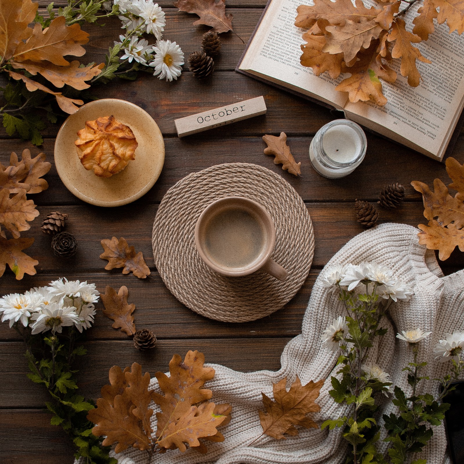 Un primer plano de una taza de café en una mesa con hojas de otoño (hoja, mesa, decoración navideña, utensilios de mesa, comida)