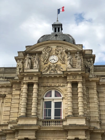 Fachada clássica de um palácio governamental com torre do relógio e bandeira francesa